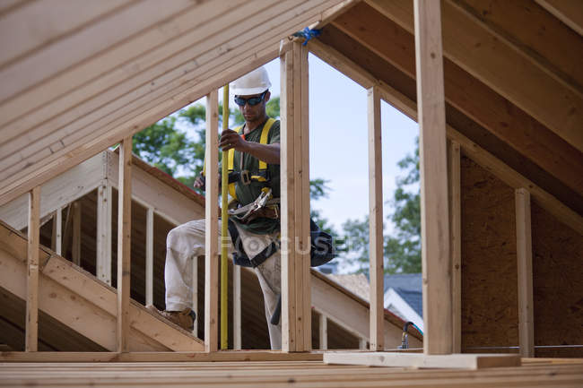 Borchie da parete di misurazione carpentiere ispanico in una casa in costruzione — Foto stock