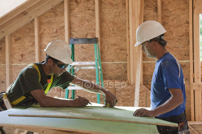 Плотники, измеряющие наружные оболочки на строительной площадке — стоковое фото