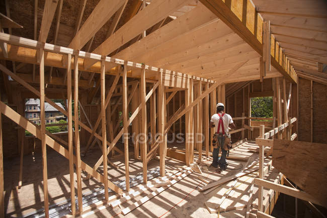Carpinteiro hispânico trabalhando no piso superior em uma casa em construção — Fotografia de Stock