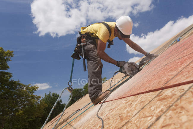 Spanisch Tischler mit einer Kreissäge auf einer Dachhülle an einem im Bau befindlichen Haus — Stockfoto