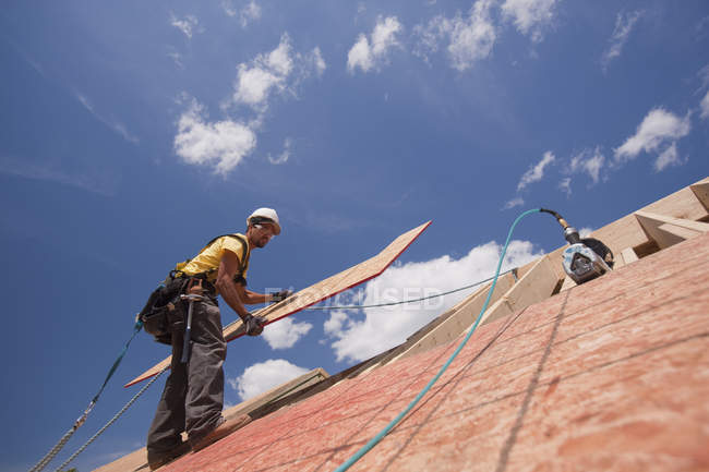 Carpinteiro que instala o painel da forma de L no telhado de uma casa em construção — Fotografia de Stock