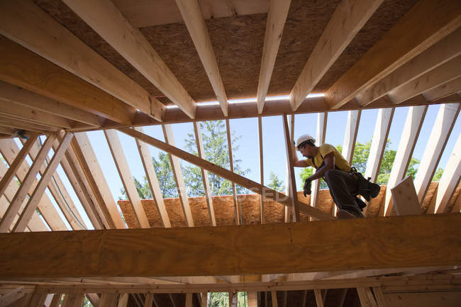 Латиноамериканский плотник с помощью циркулярной пилы на стропиле в строящемся доме — стоковое фото