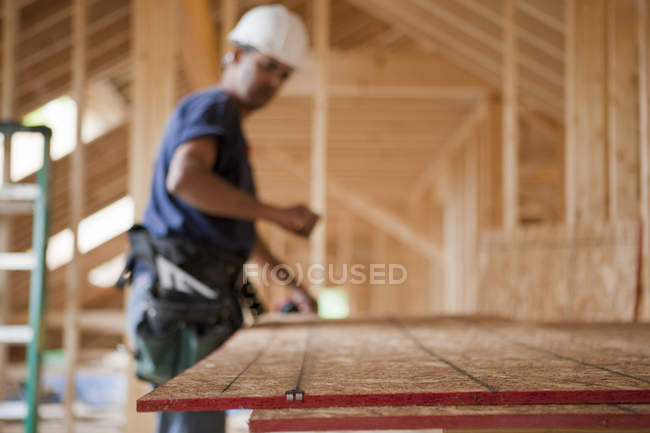 Hispanic carpenter snapping a string line on a roof panel at a house under construction — Stock Photo