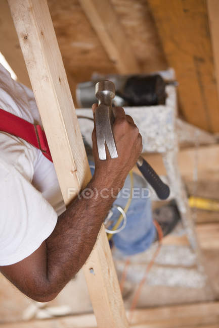 Carpinteiro hispânico usando um martelo em uma casa em construção — Fotografia de Stock