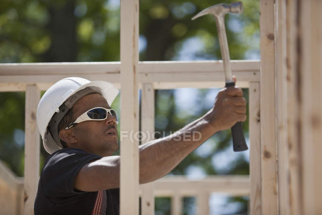 Carpenter nailing on wood framing at a construction site — Stock Photo