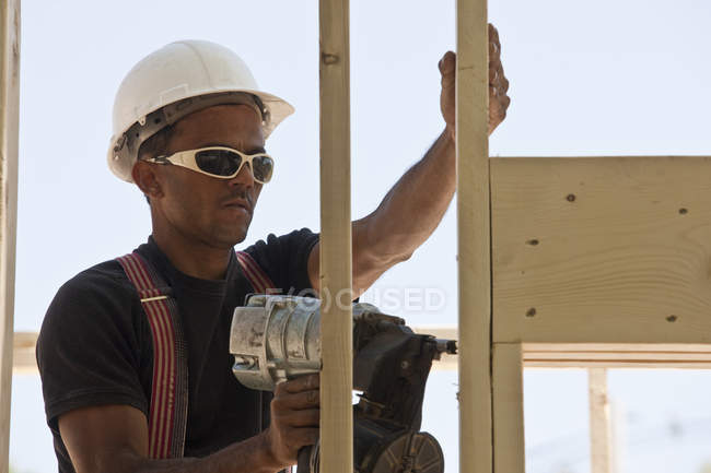 Menuisier utilisant un pistolet à ongles sur un chantier de construction — Photo de stock