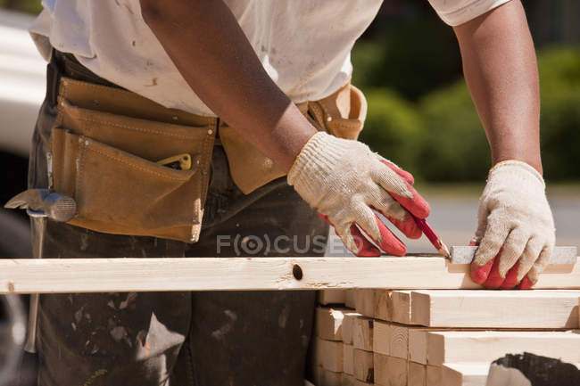 Carpenter measuring wall studs at a construction site — Stock Photo