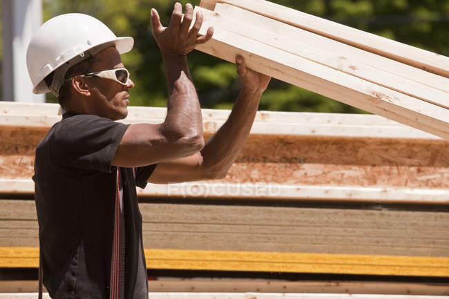 Carpenter lifting wall studs at a building construction site — Stock Photo