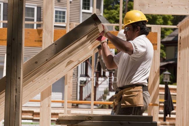 Charpentier levant le cadre de mur sur un chantier de construction — Photo de stock