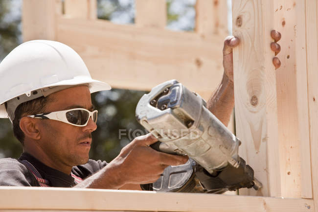 Carpenter using a nail gun at a construction site — Stock Photo