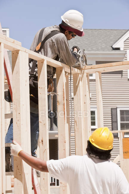 Carpenters sawing a wall stud at a building construction site — Stock Photo