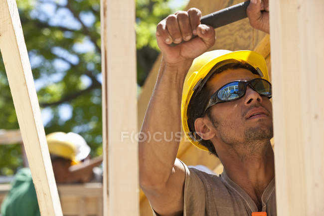 Плотник работает с молотком на строительной площадке — стоковое фото