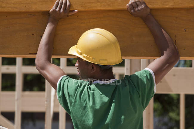 Плотник поднимает ламинированный луч на строительной площадке — стоковое фото