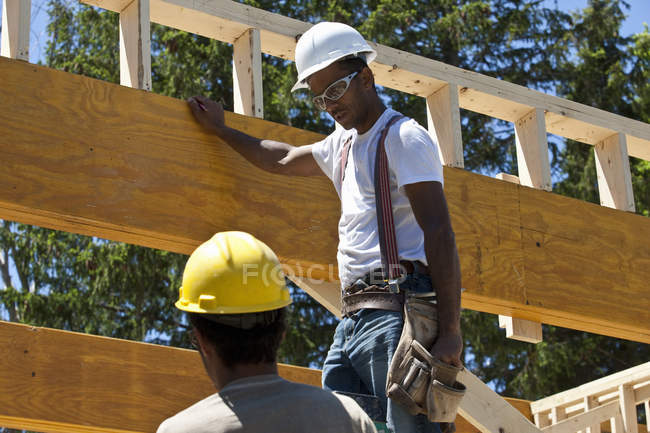 Carpinteiros colocando vigas em um canteiro de obras — Fotografia de Stock