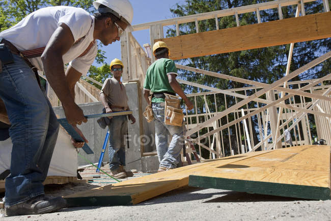 Charpentiers travaillant sur un faisceau de laminage sur un chantier de construction — Photo de stock