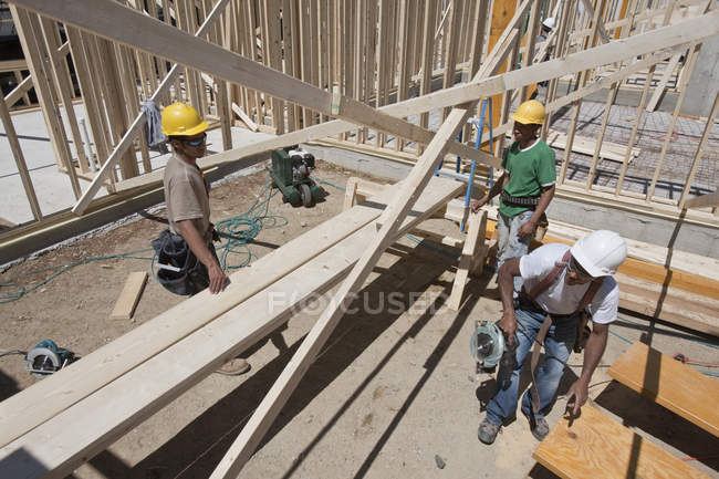 Carpinteros enmarcando una casa en un sitio de construcción de edificios - foto de stock