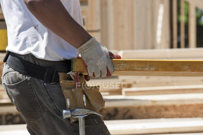 Carpinteiro levantando um feixe laminado em um canteiro de obras — Fotografia de Stock