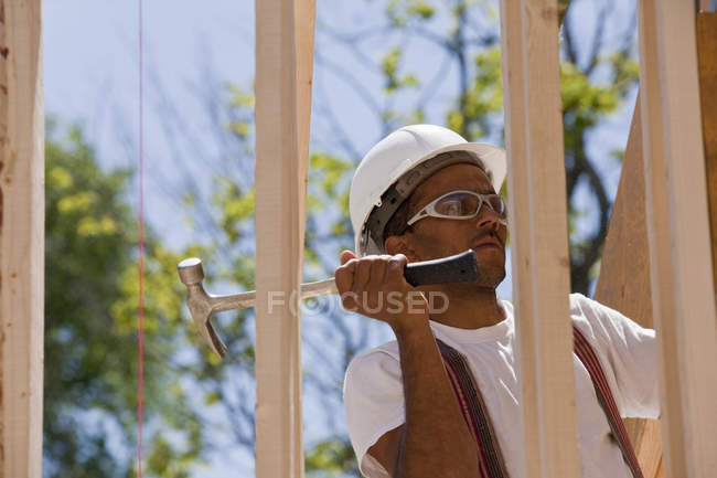 Carpinteiro usando martelo de enquadramento em uma moldura da casa — Fotografia de Stock