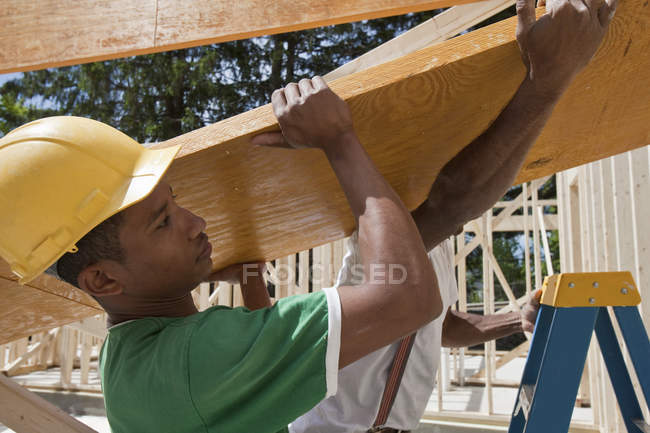 Плотники поднимают ламинированный луч на строительной площадке — стоковое фото