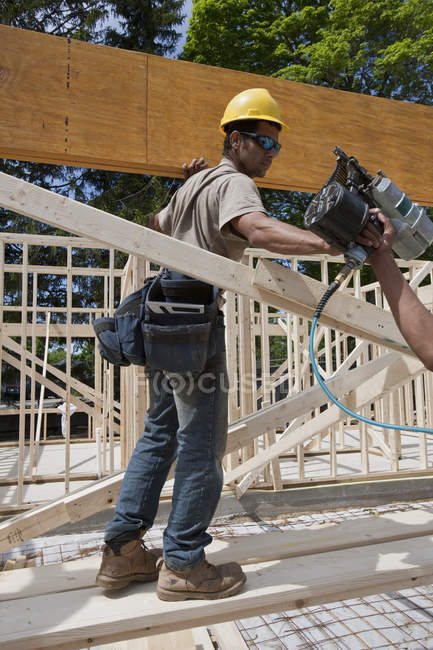 Carpenter preparing to nail a laminated beam in place — Stock Photo
