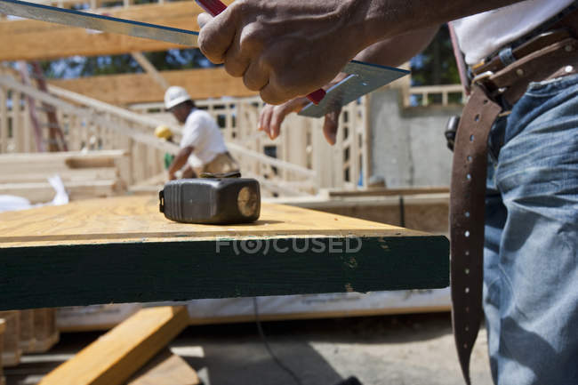Carpinteiro segurando quadrado de aço em um canteiro de obras — Fotografia de Stock