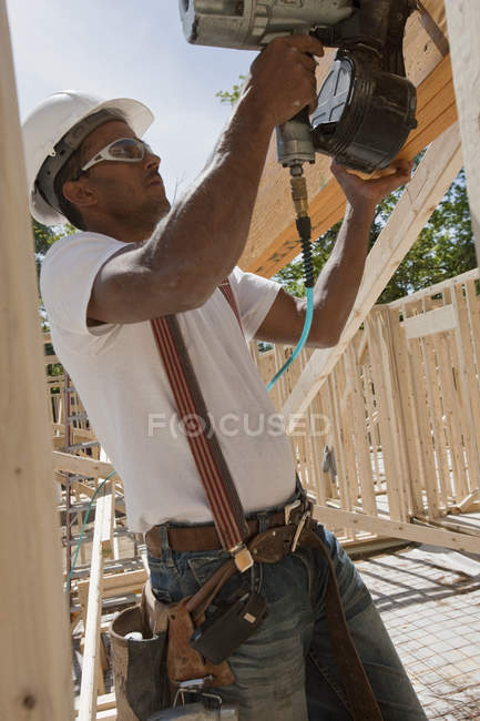 Menuisier utilisant un pistolet à ongles sur un chantier de construction — Photo de stock