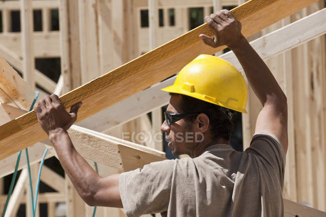 Carpenter lifting a laminated beam at a construction site — Stock Photo