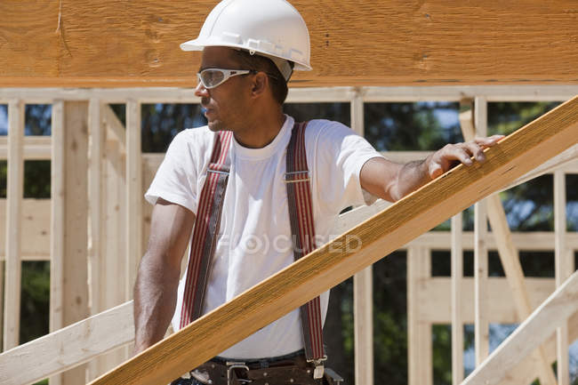 Carpenter lifting a laminated beam at a construction site — Stock Photo