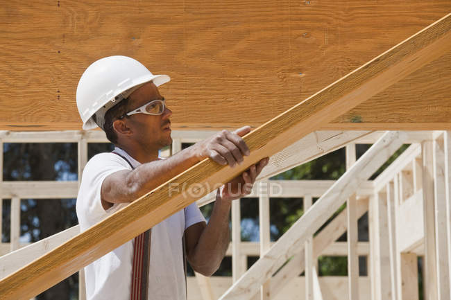 Плотник поднимает ламинированный луч на строительной площадке — стоковое фото