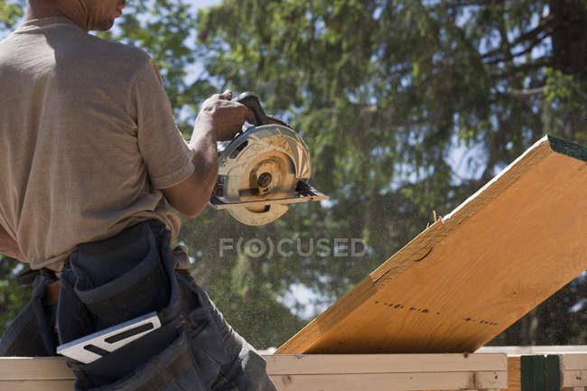 Carpenter sawing a beam at a construction site — Stock Photo
