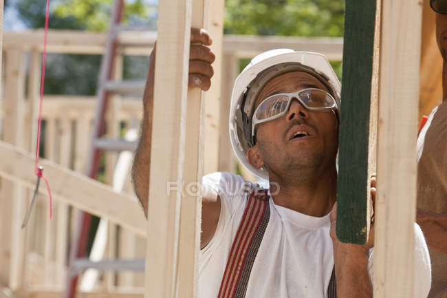 Плотник поднимает балку на строительной площадке — стоковое фото