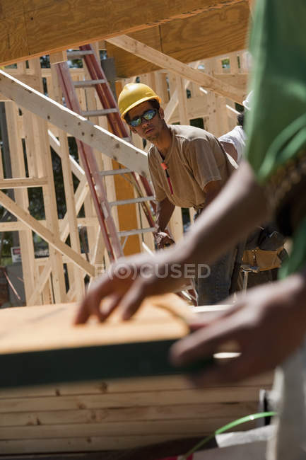 Charpentiers mesurant la poutre sur un chantier de construction — Photo de stock