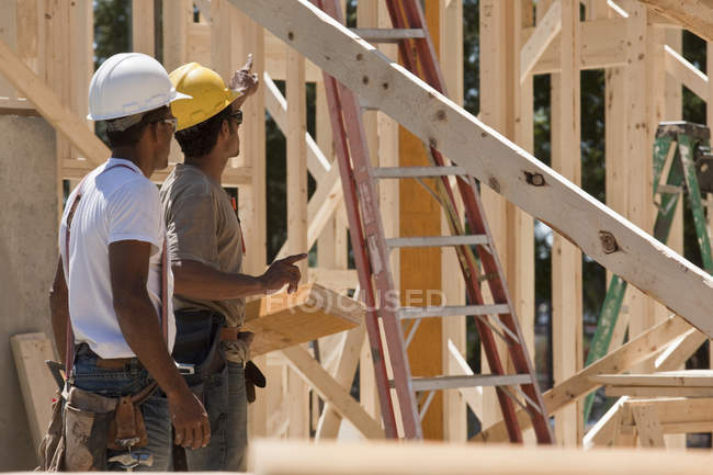 Carpinteros de pie en un sitio de construcción de edificios - foto de stock