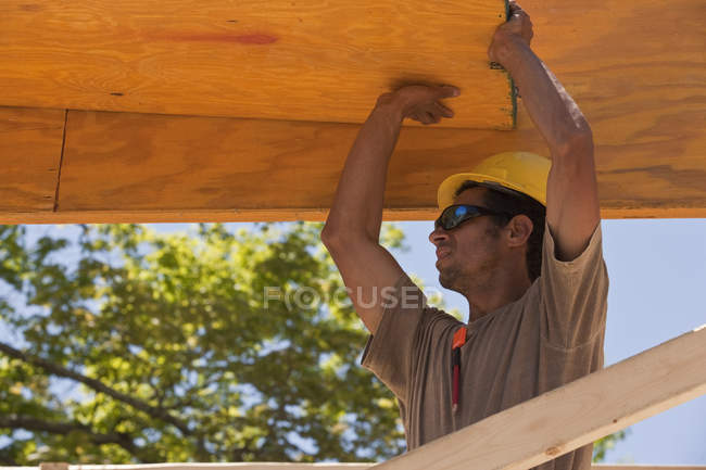Carpenter lifting a beam at a building construction site — Stock Photo