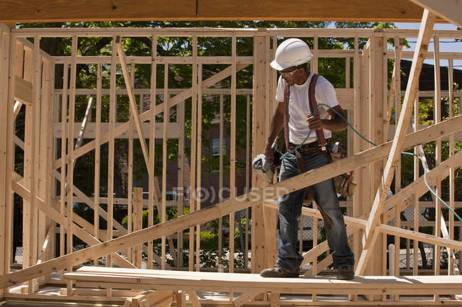 Carpenter standing at a construction site holding a nail gun — Stock Photo