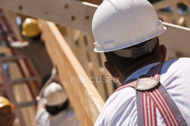 Carpinteiros levantando uma viga em um canteiro de obras — Fotografia de Stock