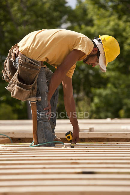 Carpinteiro de madeira de medição em um canteiro de obras — Fotografia de Stock