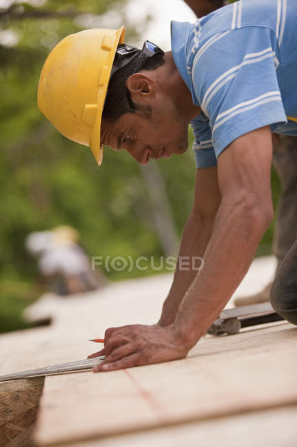 Carpinteiro fazendo medições usando triângulo em um canteiro de obras — Fotografia de Stock