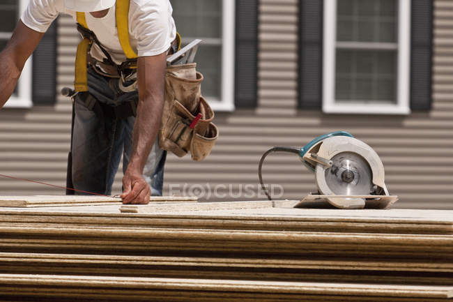 Menuisier utilisant une ligne à pression avant sciage sur un chantier de construction — Photo de stock