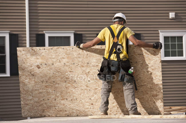 Falegname posizionare un pannello di particelle in un cantiere edile — Foto stock