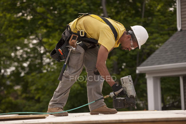 Carpenter using a nail gun at a building construction site — Stock Photo
