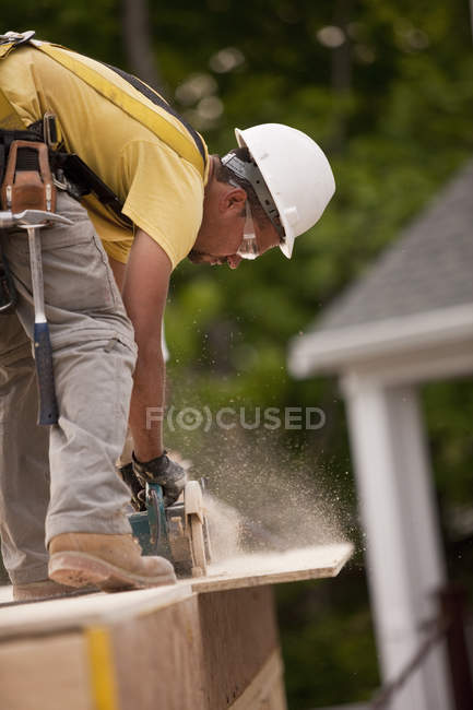 Carpenter sawing a particle board at a building construction site — Stock Photo