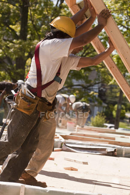 Charpentiers levant des charpentes sur un chantier de construction — Photo de stock