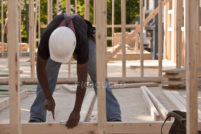 Misure di marcatura falegname su legno in un cantiere edile — Foto stock