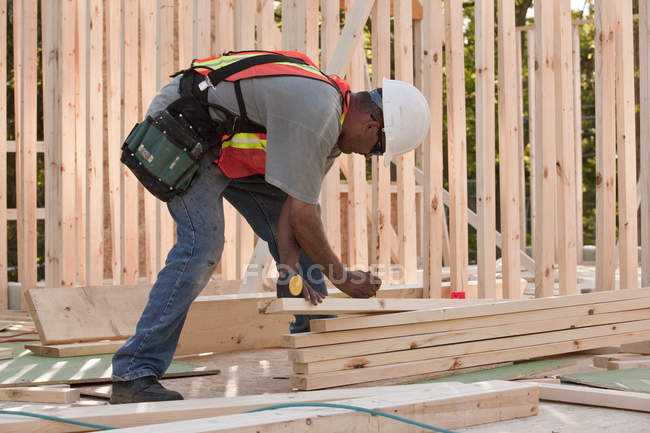 Menuisier marquant le bois sur un chantier de construction — Photo de stock