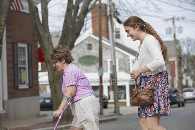 Mujer con parálisis cerebral caminando con su hermana por la ciudad - foto de stock