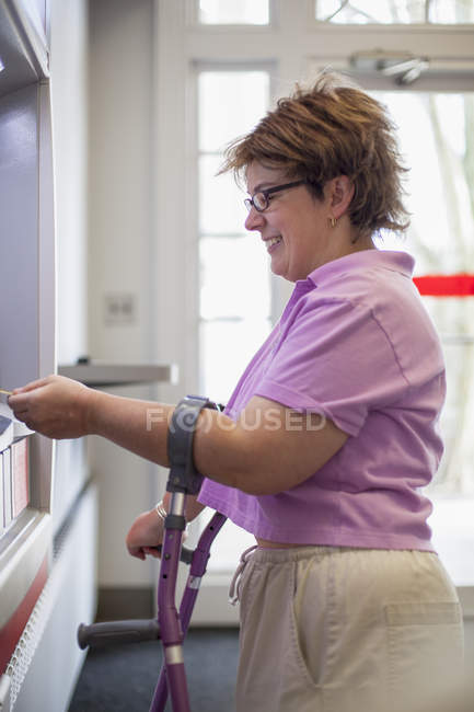Mujer con parálisis cerebral usando un cajero automático - foto de stock