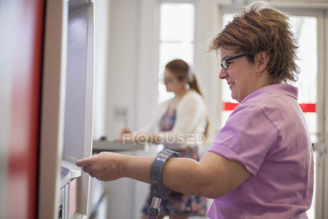 Donna con paralisi cerebrale utilizzando un bancomat — Foto stock
