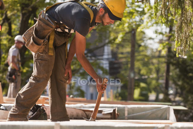 Carpenter using a claw hammer at a construction site — Stock Photo