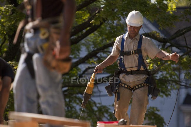Carpinteros usando una sierra recíproca en un sitio de construcción de edificios - foto de stock